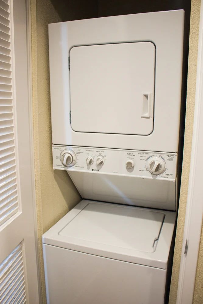 A washer and dryer are stacked on top of each other in a closet.