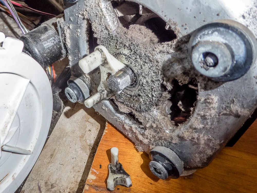 A close up of a dirty motor on a wooden table.