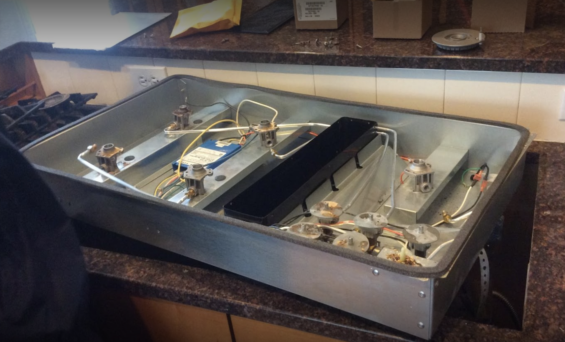 A stove top oven is being repaired on a kitchen counter.