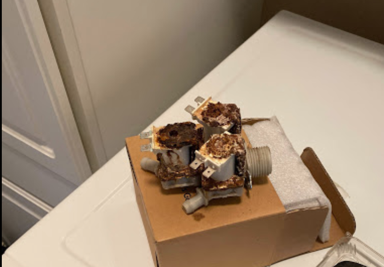 A cardboard box with a bunch of rusty valves on top of a washing machine.