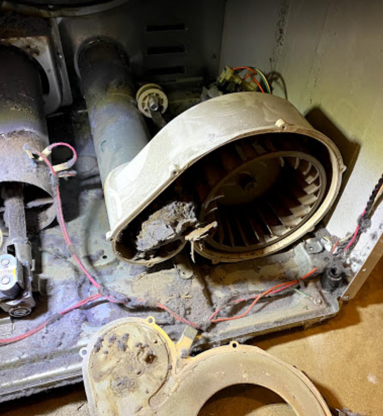 A close up of a dirty machine with a fan and wires.