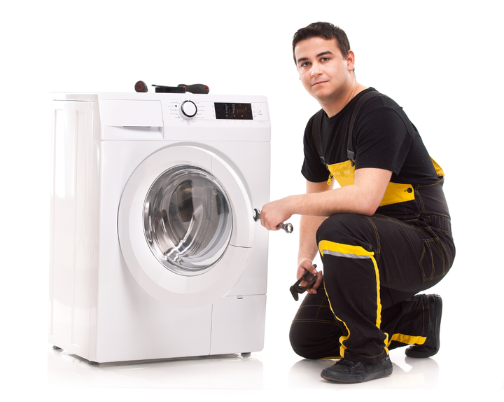 A man is repairing a washing machine with a wrench.