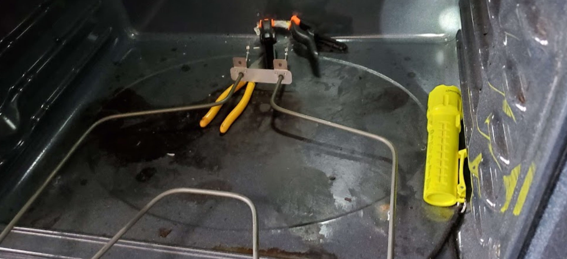 A pair of pliers is sitting on top of a dirty oven.