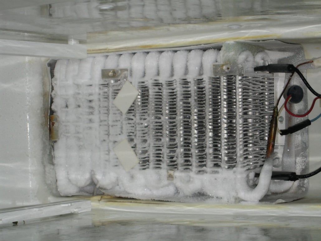 The inside of a refrigerator with a lot of ice on it.