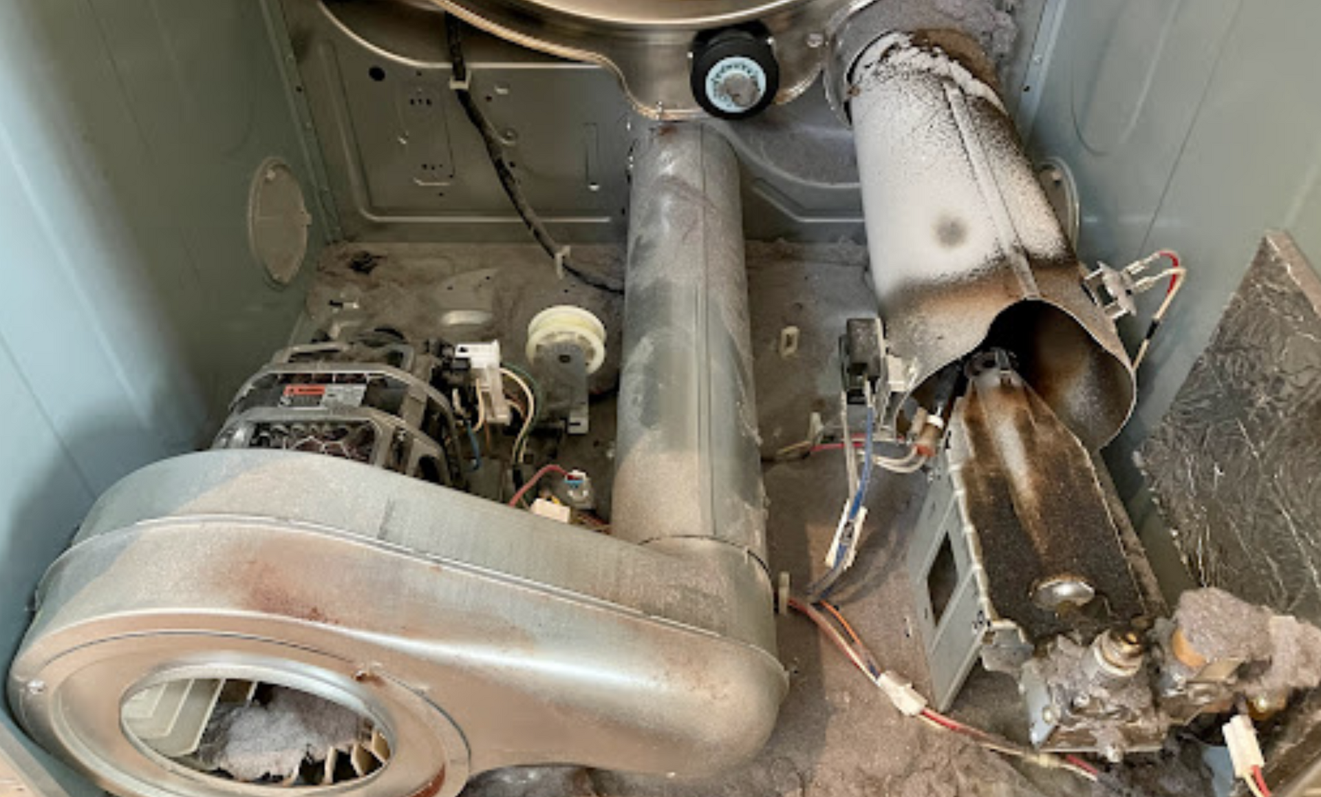 The inside of a dryer is covered in dust and dirt.