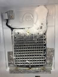 The inside of a refrigerator with ice coming out of it.