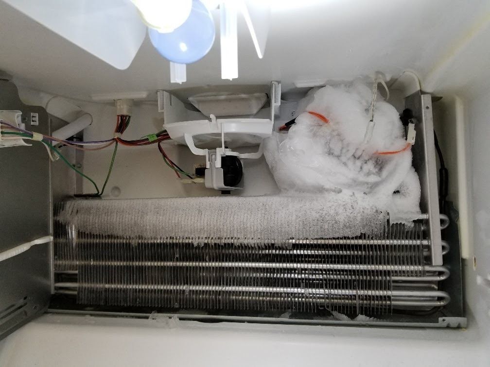 The inside of a refrigerator with a bag of ice on top of it.