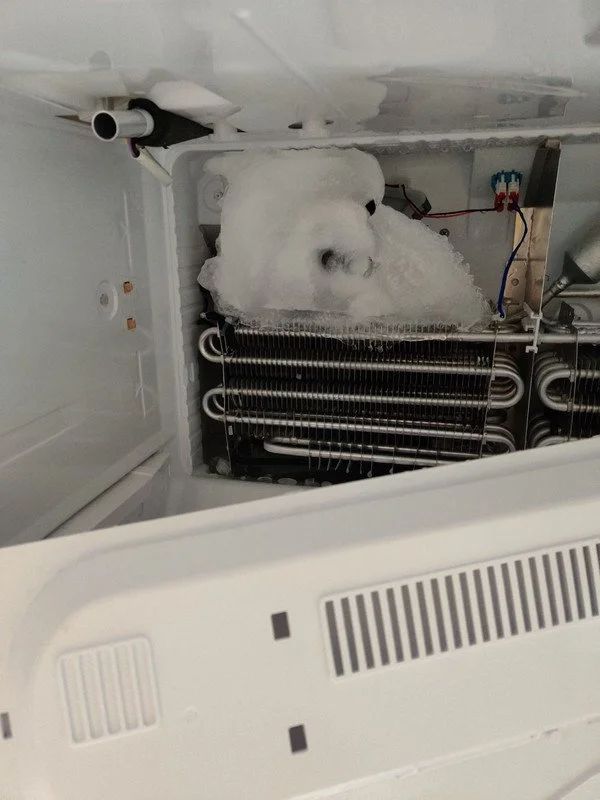 The inside of a refrigerator with a lot of ice on it.