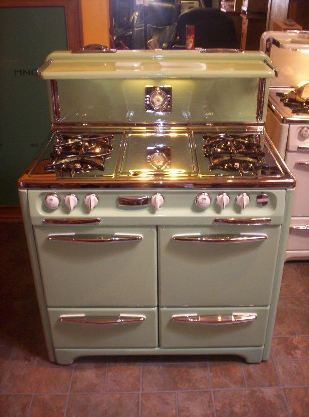A green stove with four burners and two ovens