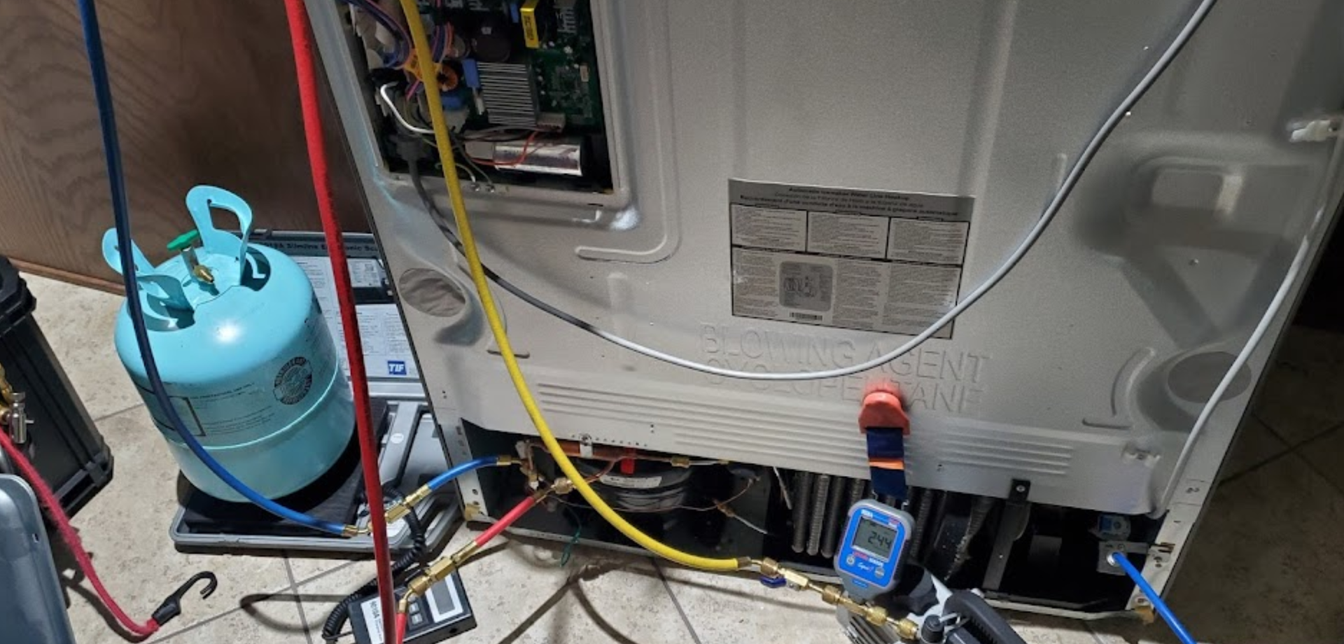 A refrigerator is being repaired in a garage.