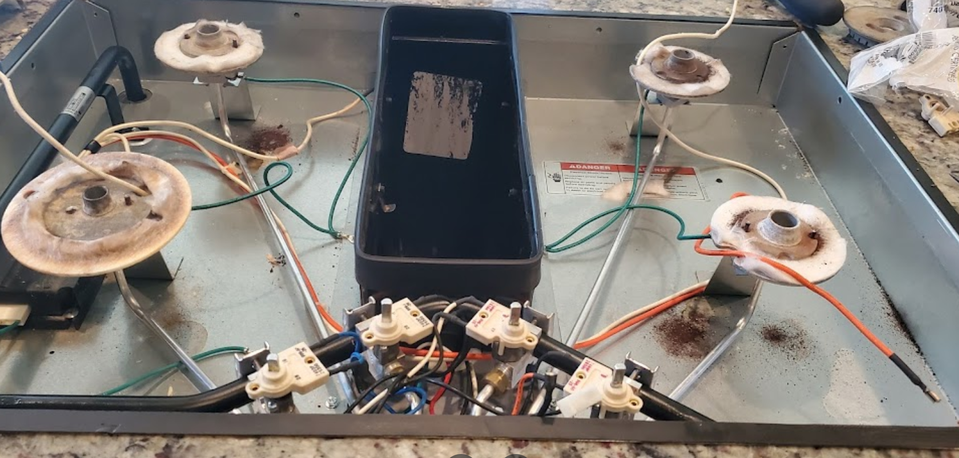 The inside of a stove with a lot of wires coming out of it.