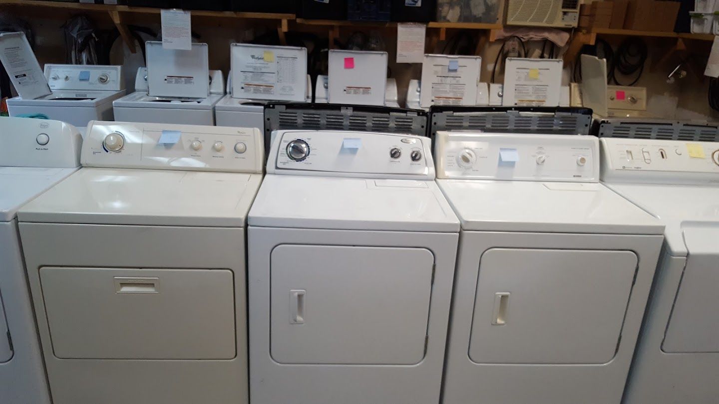 A row of white washers and dryers are lined up in a store.