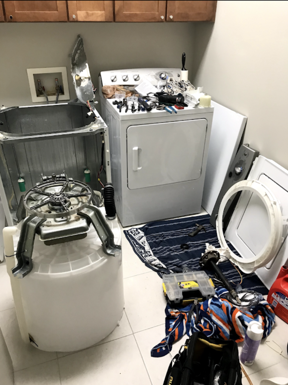 A washer and dryer are being repaired in a laundry room.