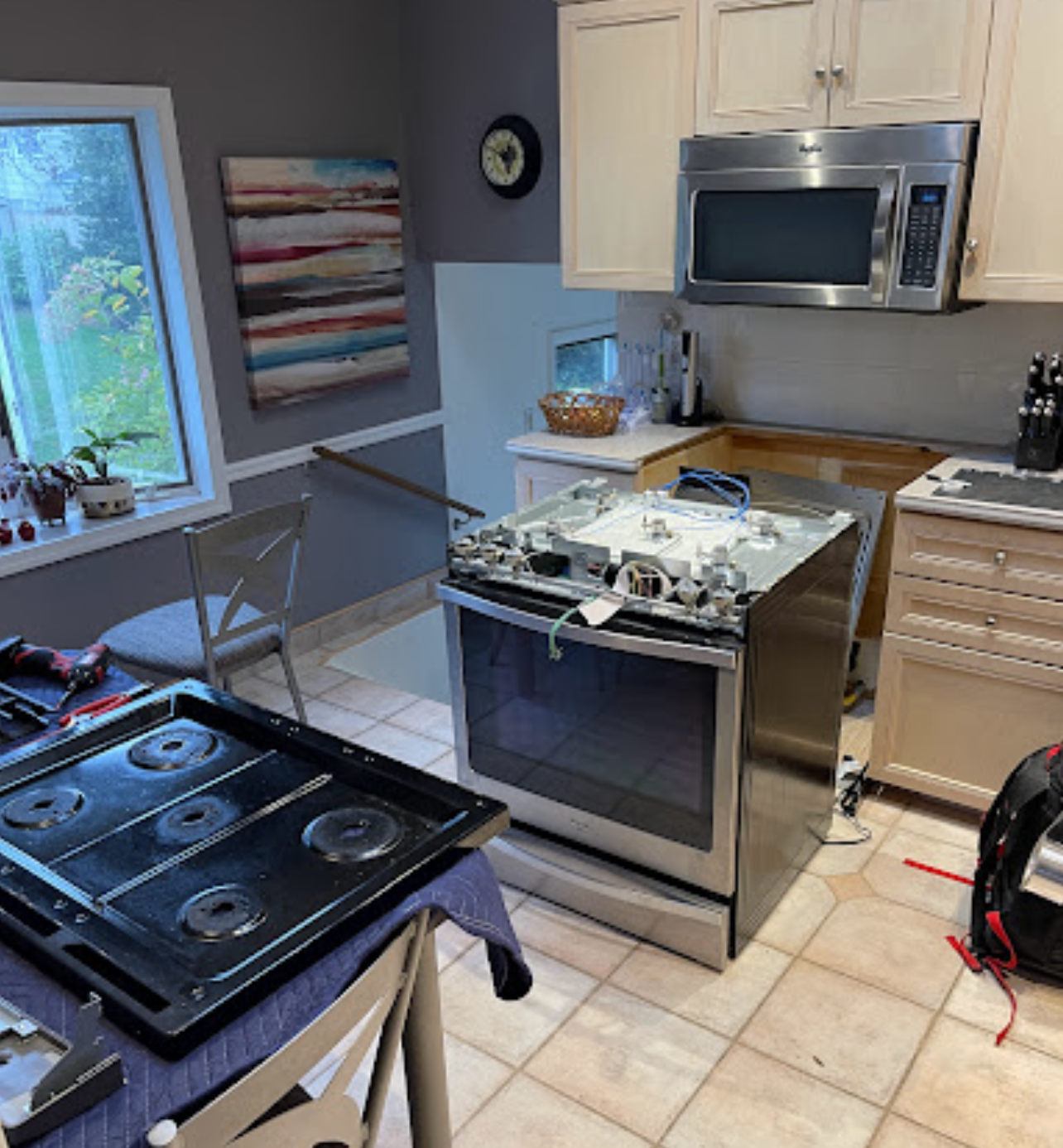 A kitchen with a stove , microwave , and cabinets.