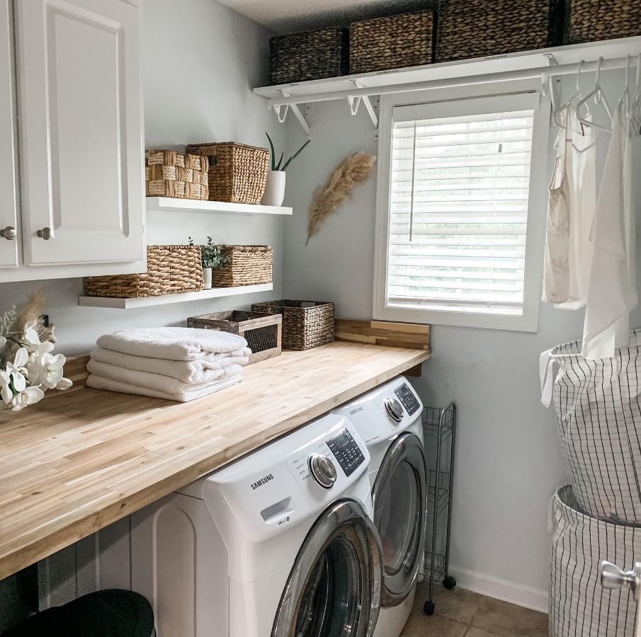 A laundry room with a washer and dryer and a wooden counter top.