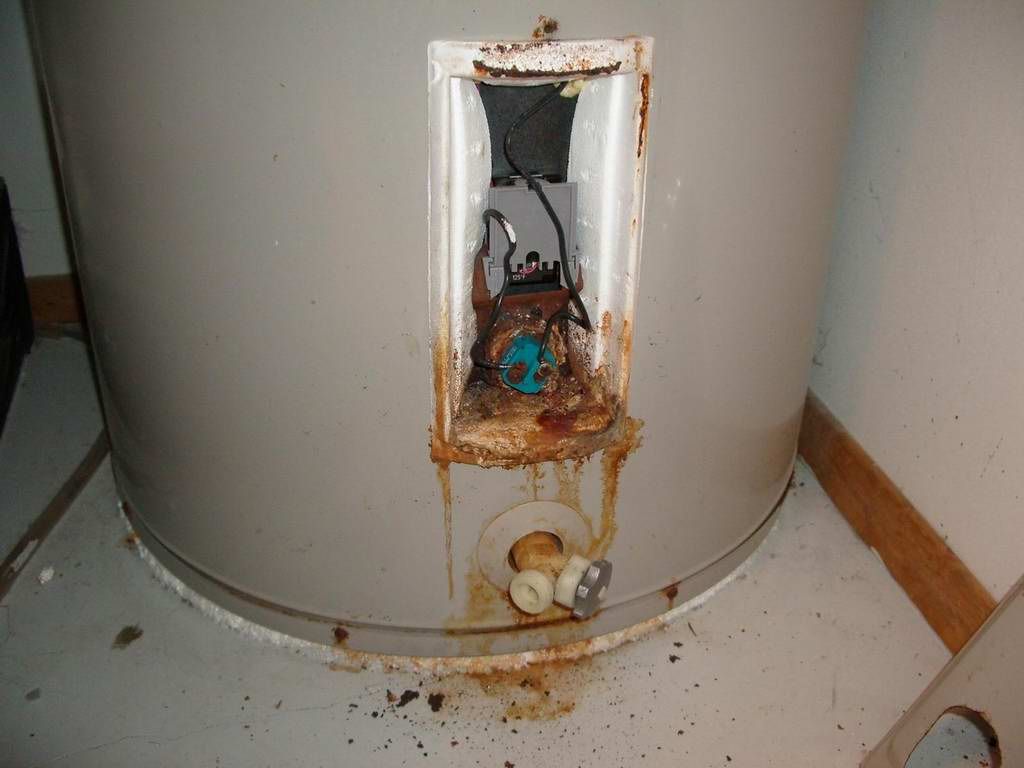A rusty water heater is sitting on the floor
