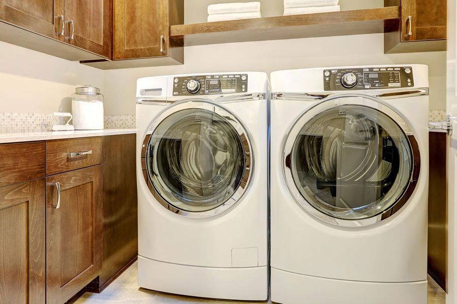A laundry room with two washing machines and a dryer.