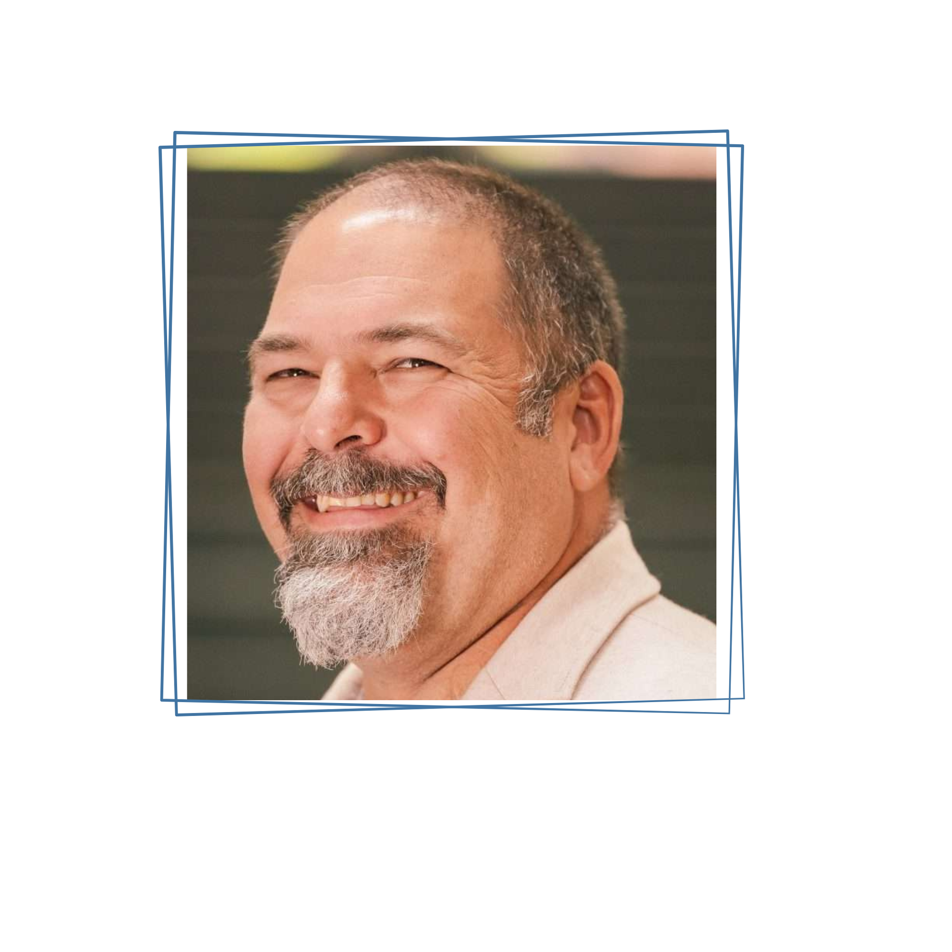 A smiling man with a graying beard and mustache, framed in a white border against a dark background.