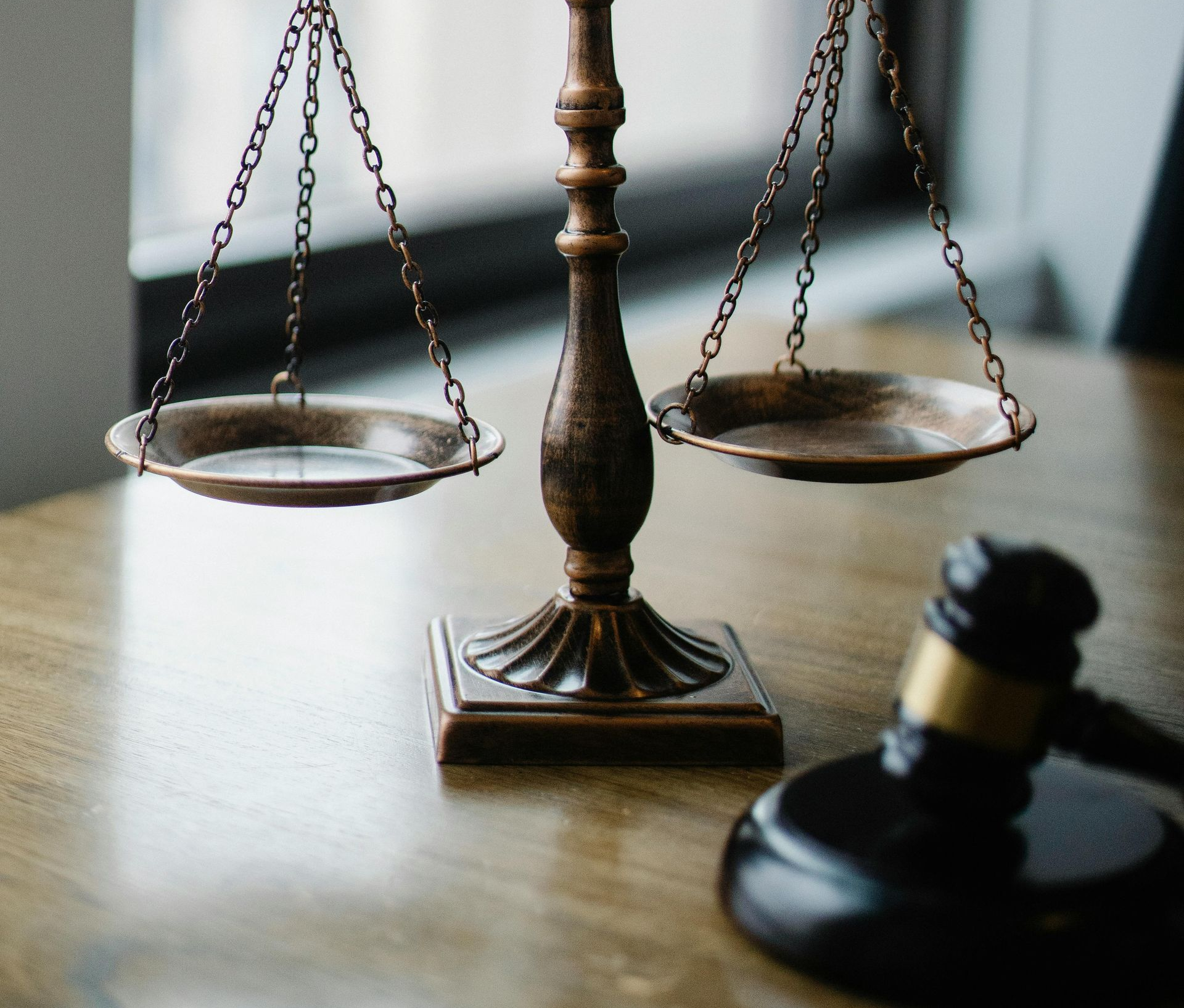 Scales of justice with empty pans and gavel on a wooden table.