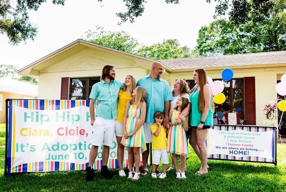 A family is standing in front of a house with balloons.