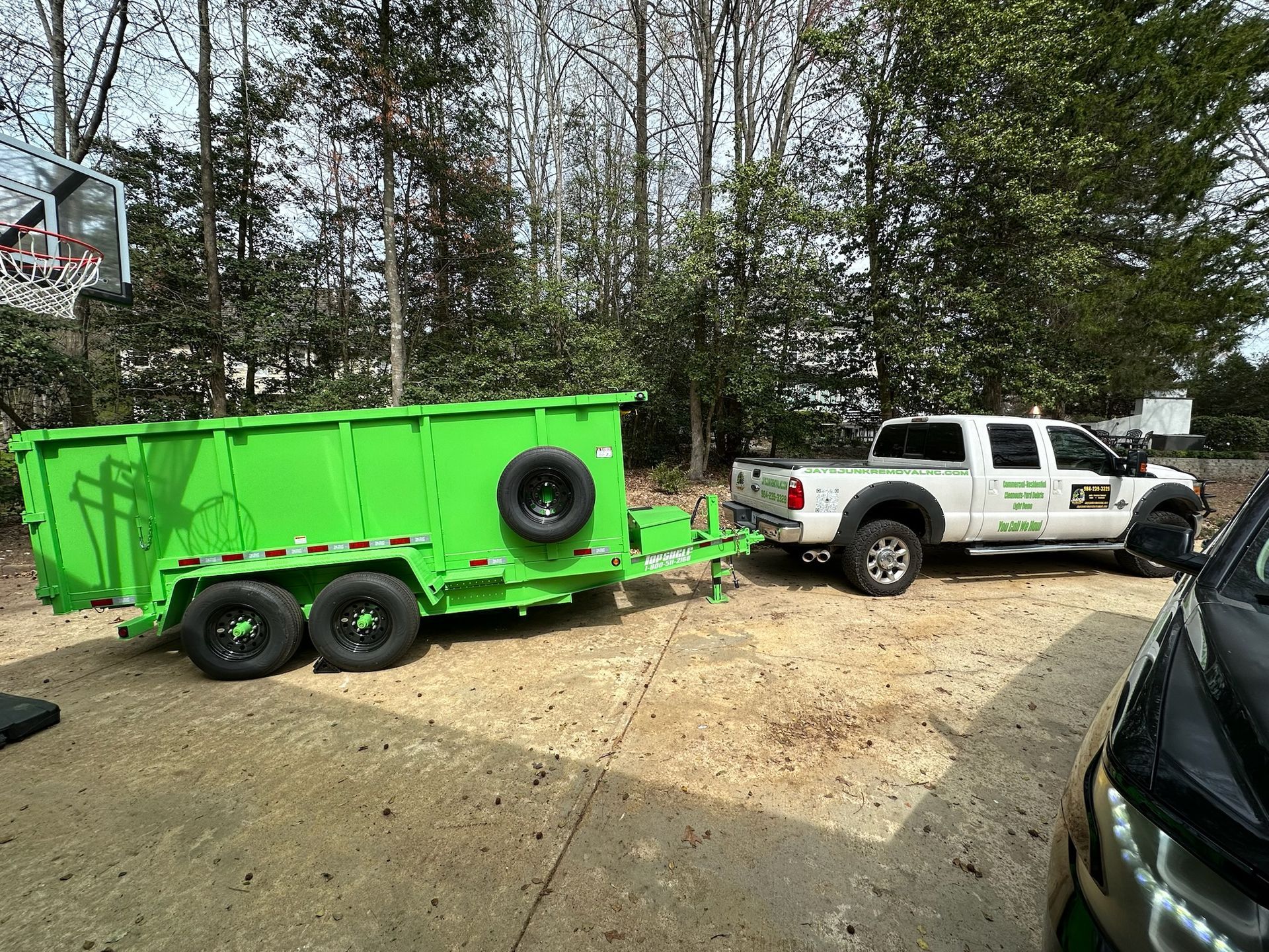 A truck is pulling a green dumpster trailer.