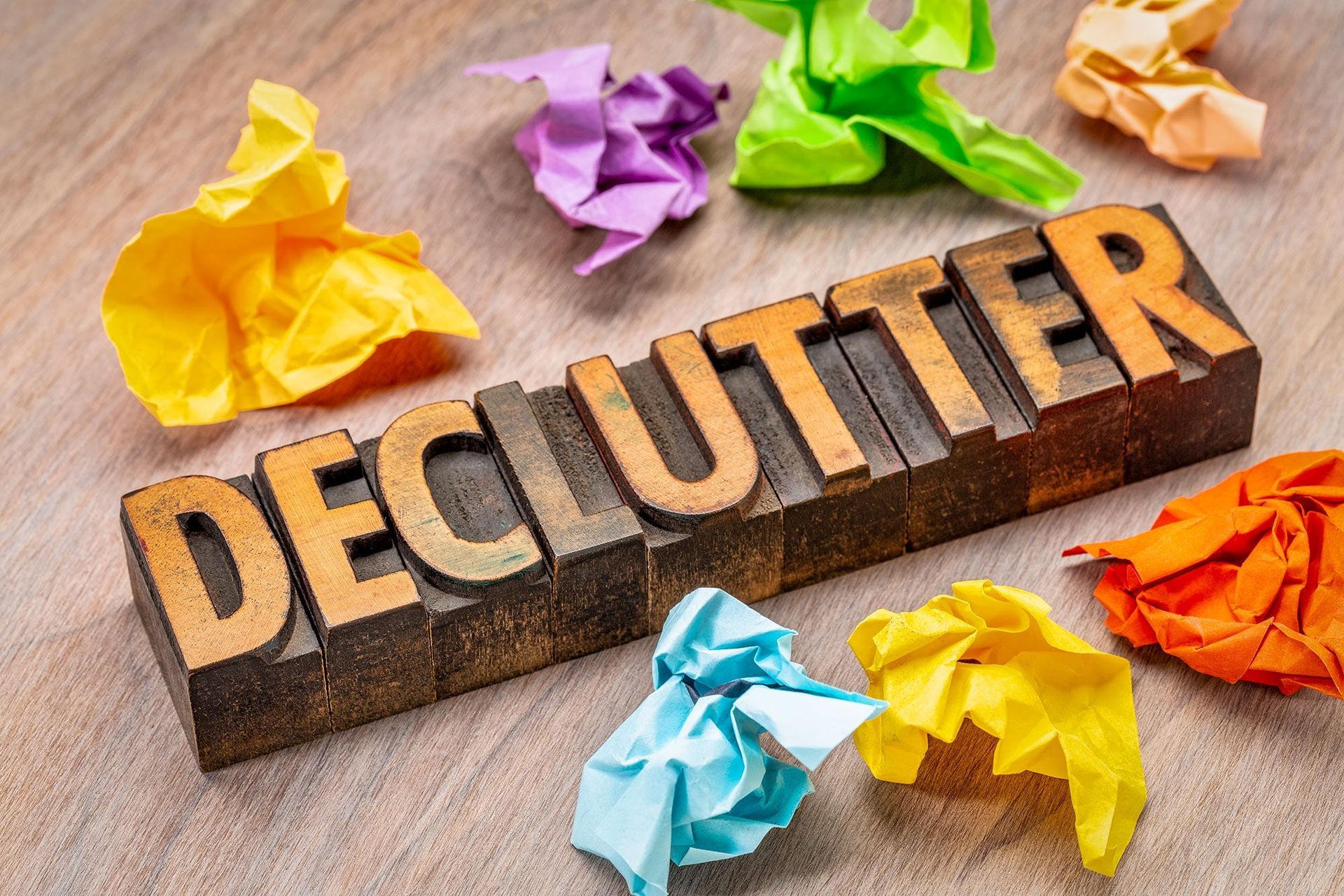 The word declutter is written in wooden letterpress type surrounded by crumpled paper.