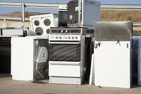 A bunch of old appliances are stacked on top of each other on the ground.