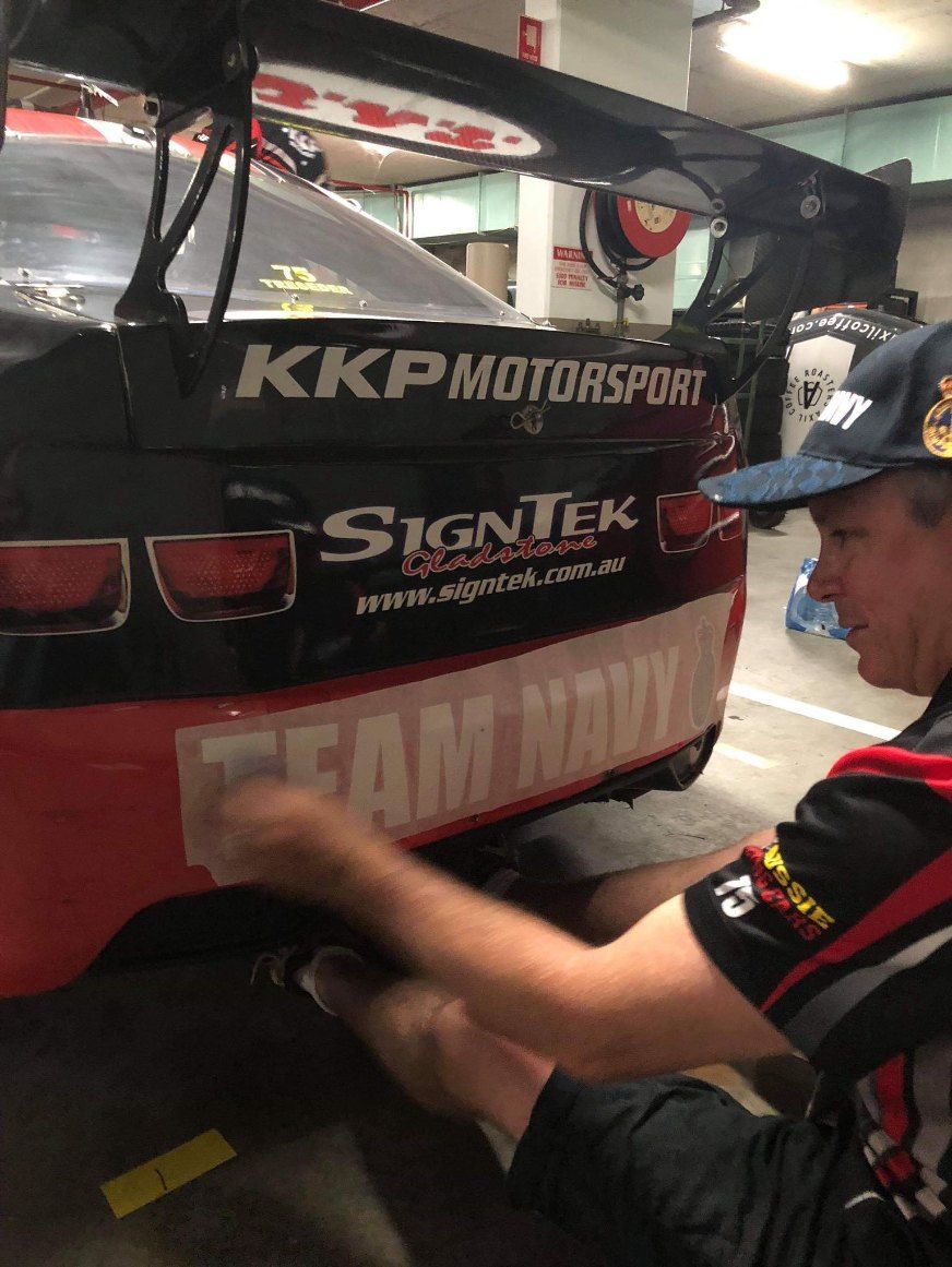 A Man is Working on a Race Car in a Garage — Signtek Gladstone in Gladstone Central, QLD