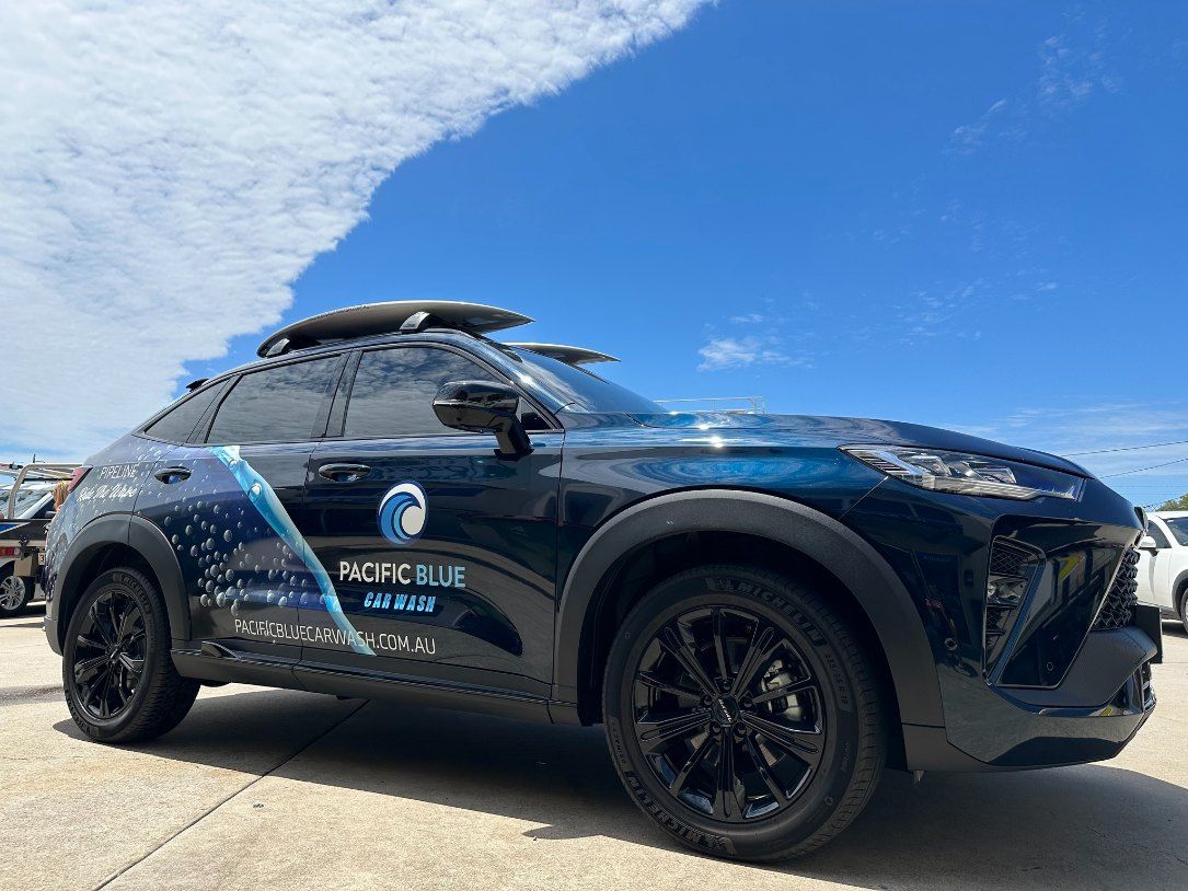 A Black Suv With a Surfboard on Top of It is Parked in a Parking Lot — Signtek Gladstone in Rockhampton, QLD
