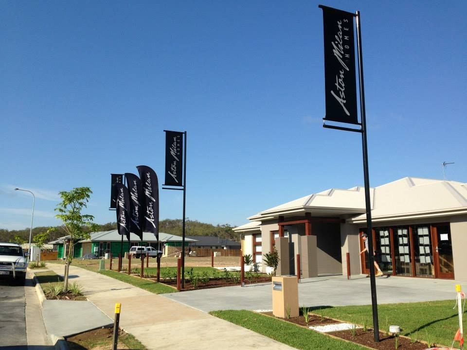 A Row of Black Flags Are Hanging From Poles in Front of a House — Signtek Gladstone in Gladstone Central, QLD