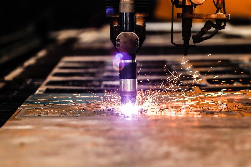 A Machine is Cutting a Piece of Metal With a Lot of Sparks Coming Out of It — Signtek Gladstone in Gladstone Central, QLD