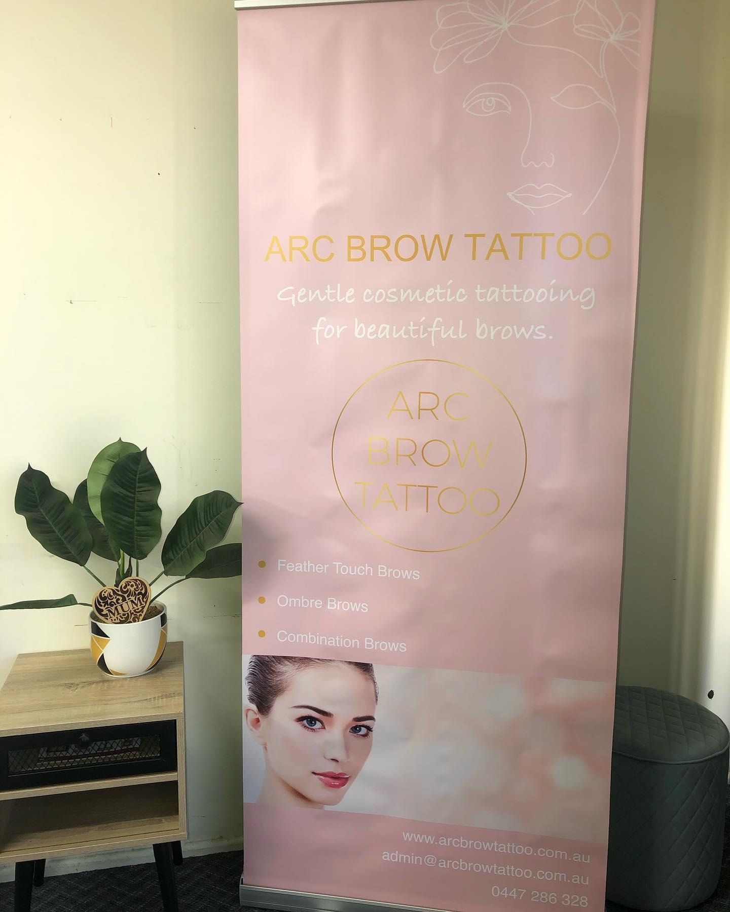 A Pink Banner is Hanging on a Wall Next to a Plant — Signtek Gladstone in Gladstone Central, QLD