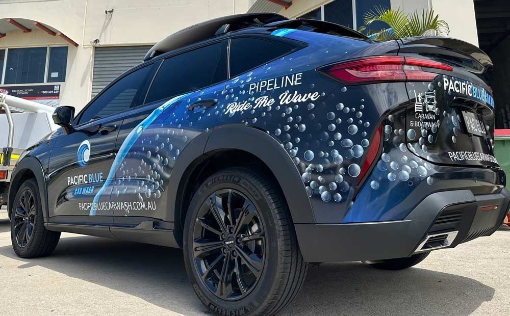 A Blue Car With Bubbles Painted on the Side is Parked in Front of a Building — Signtek Gladstone in Gladstone Central, QLD