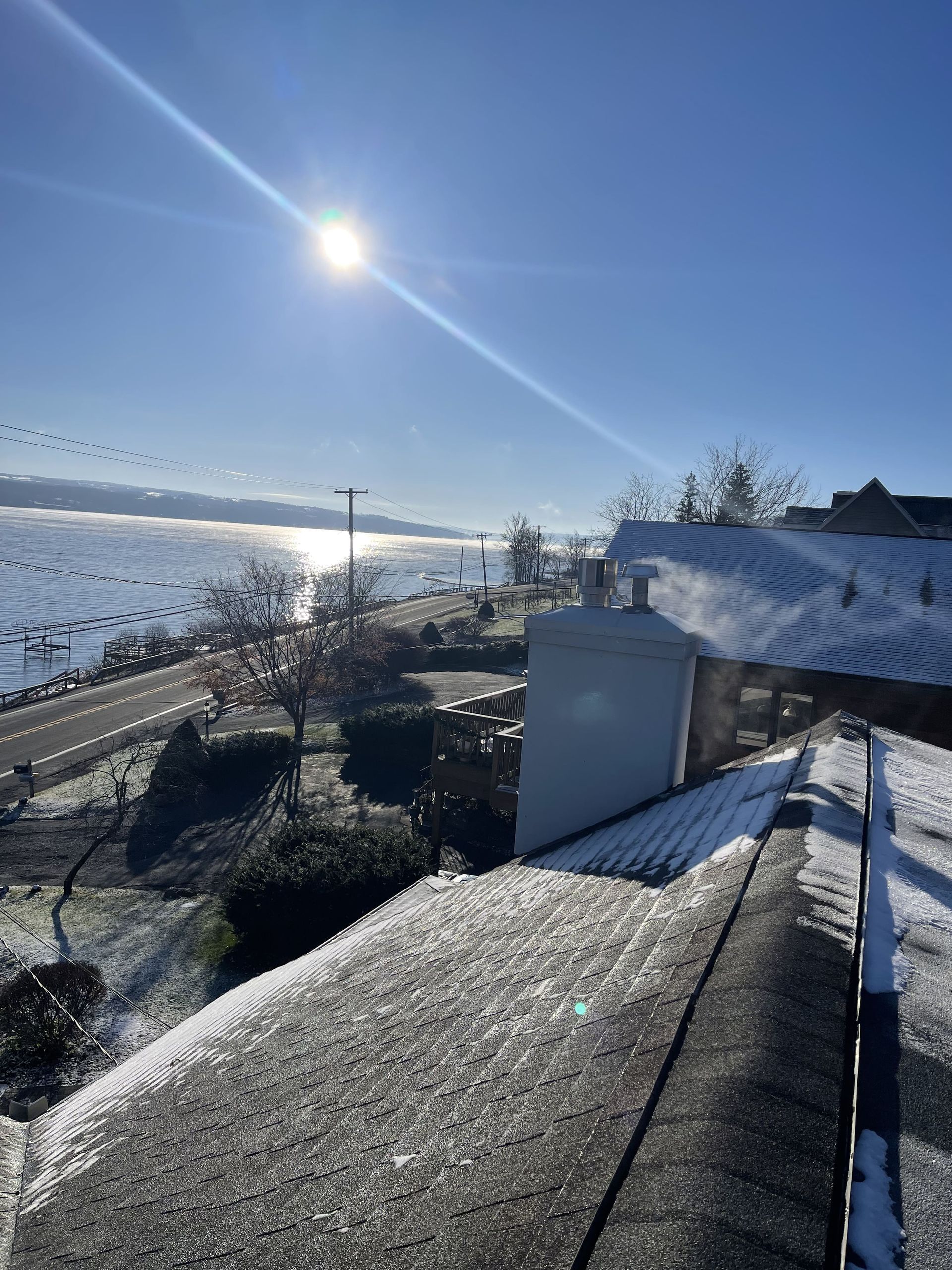 A snowy roof with a view of a body of water