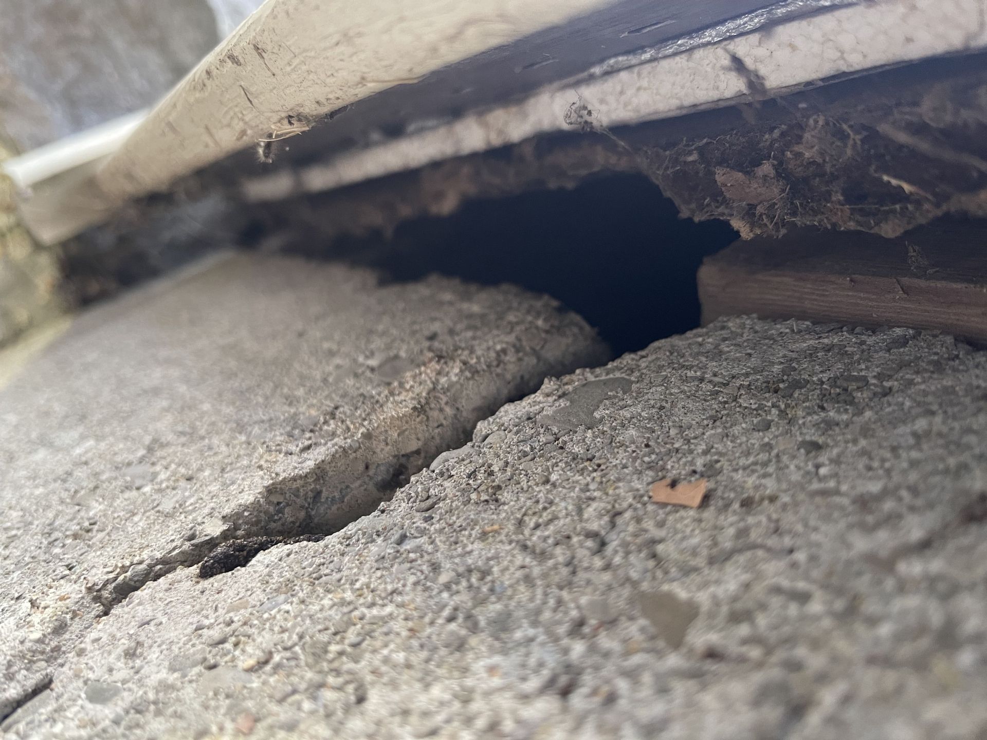 A close up of a cracked concrete surface with a hole in it.