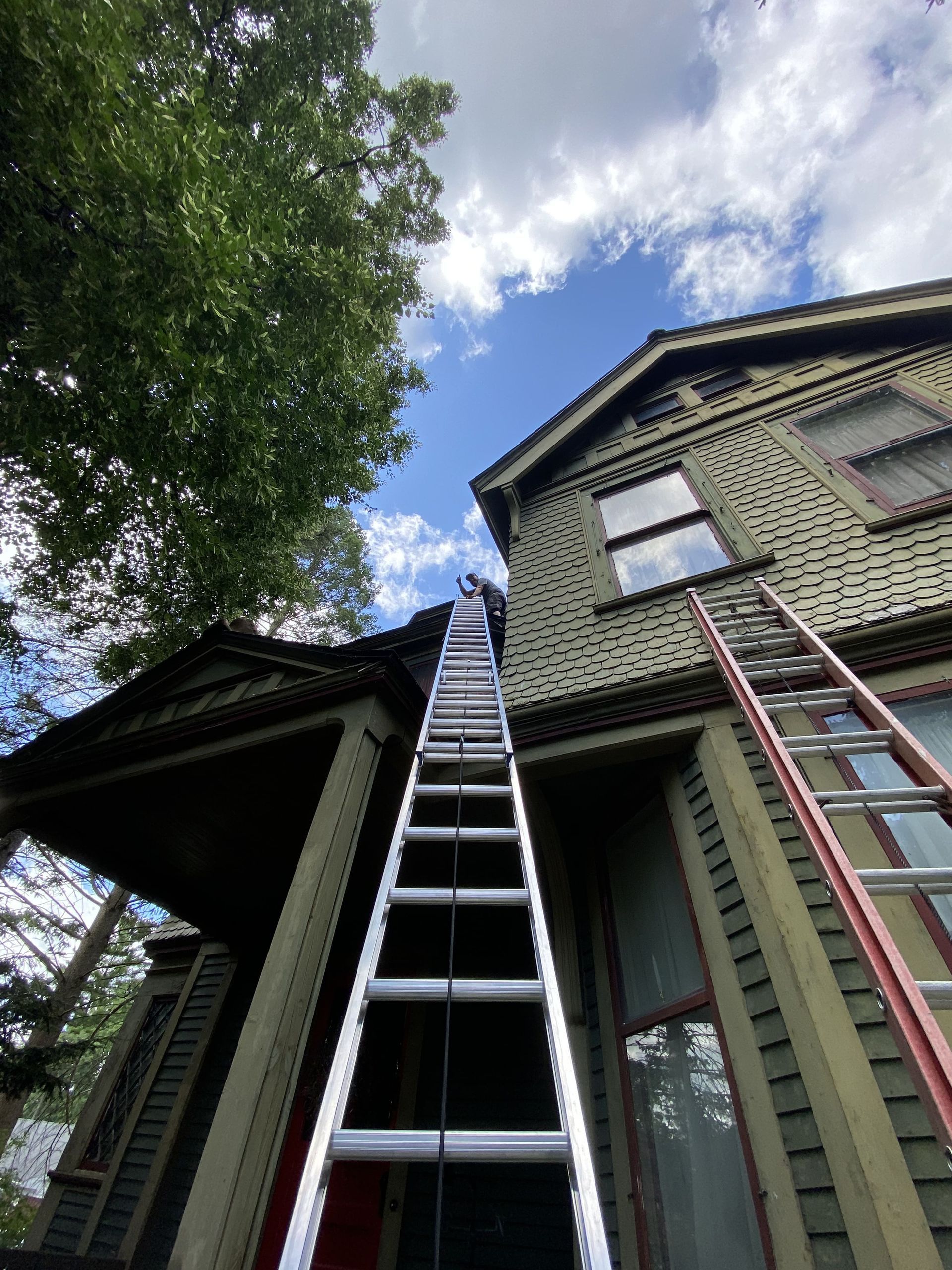 A ladder is going up to the top of a house.