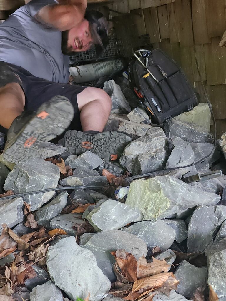A man is laying on top of a pile of rocks.
