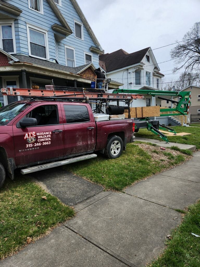 A red truck is parked in front of a blue house.