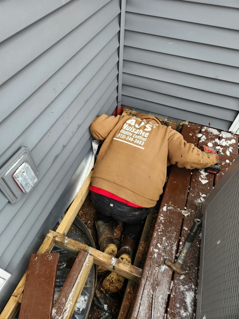 A man is laying on a wooden deck next to a house.