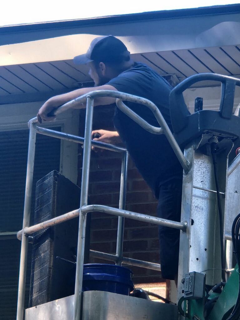 A man is standing in a bucket on top of a crane.
