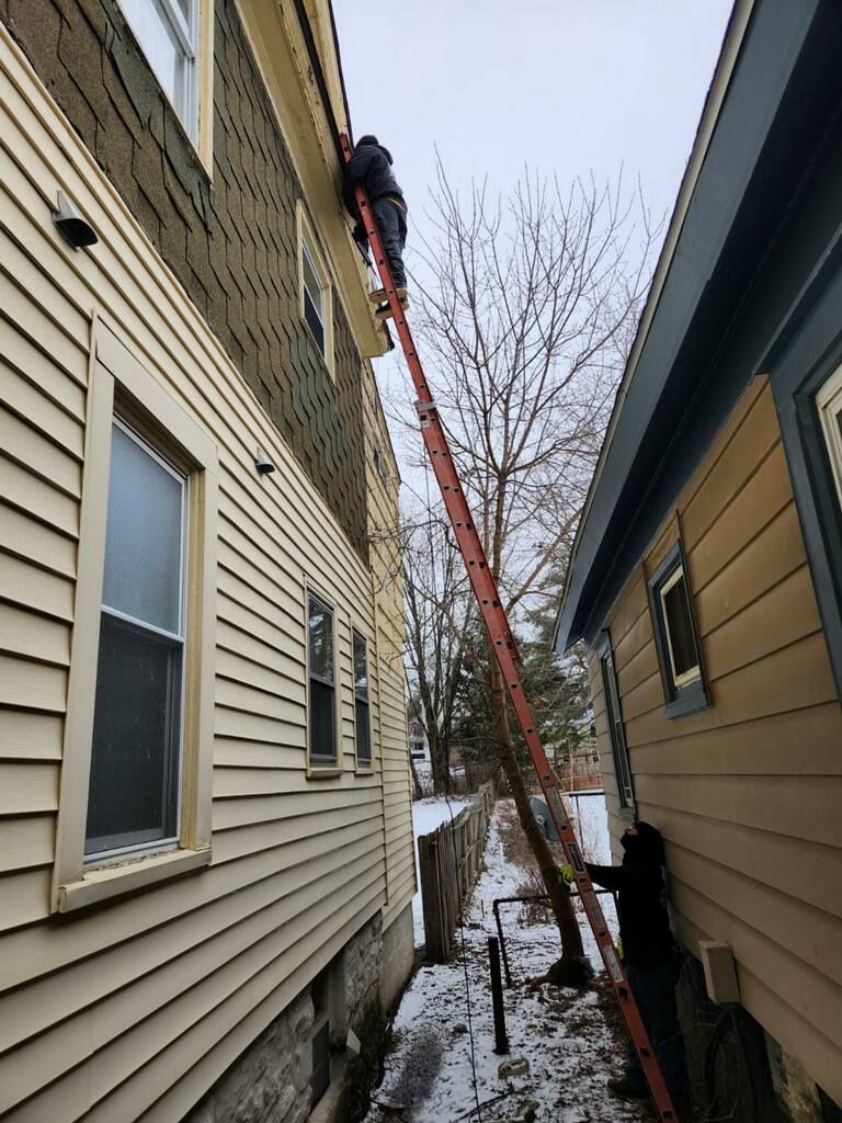 A man is standing on a ladder between two houses.