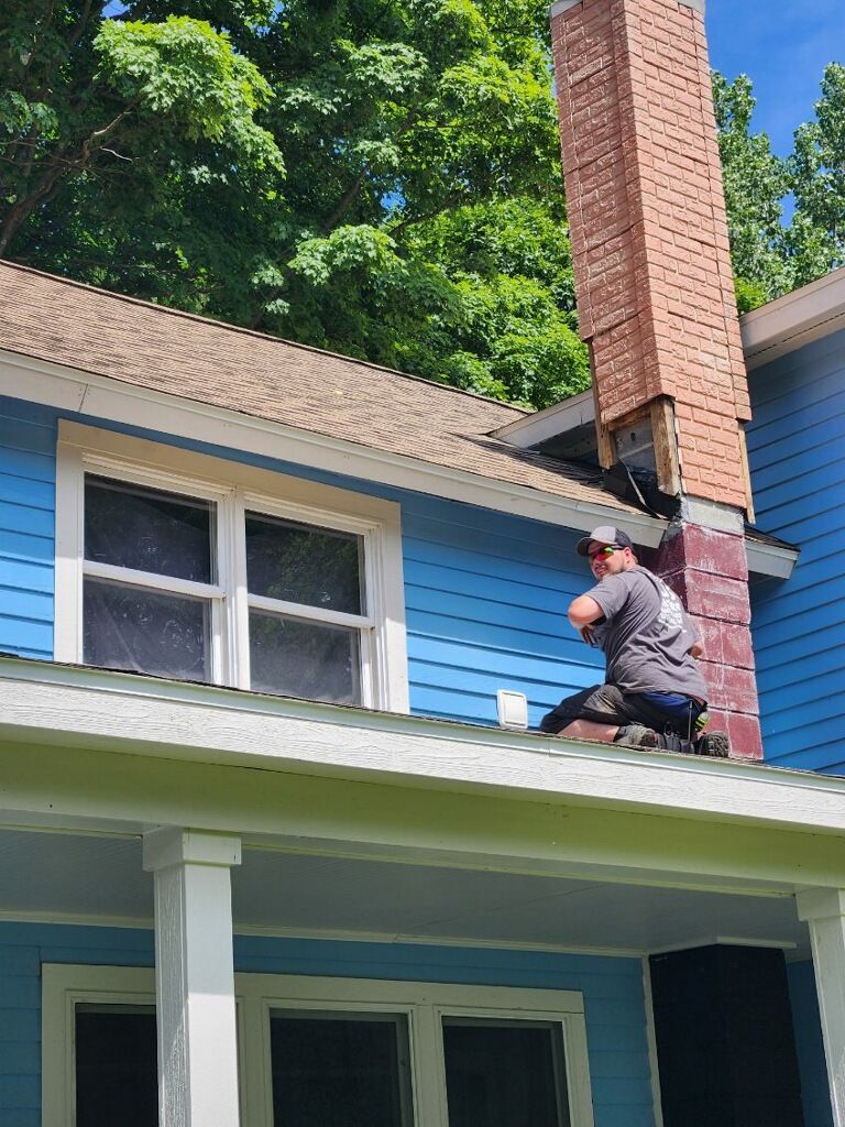 A man is working on the roof of a blue house.