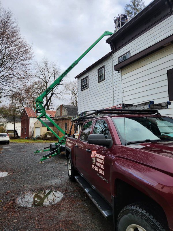 Green lift extending to a two-story white house; burgundy truck with logo parked on gravel.