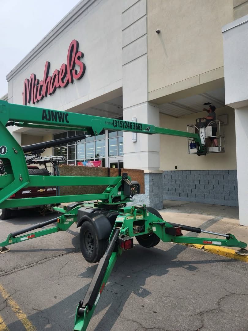 Green lift platform with a person working on the exterior of a Michaels store.