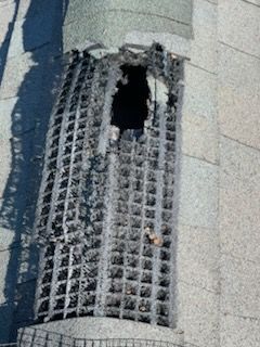 Damaged roof vent with a large hole. Gray and black.
