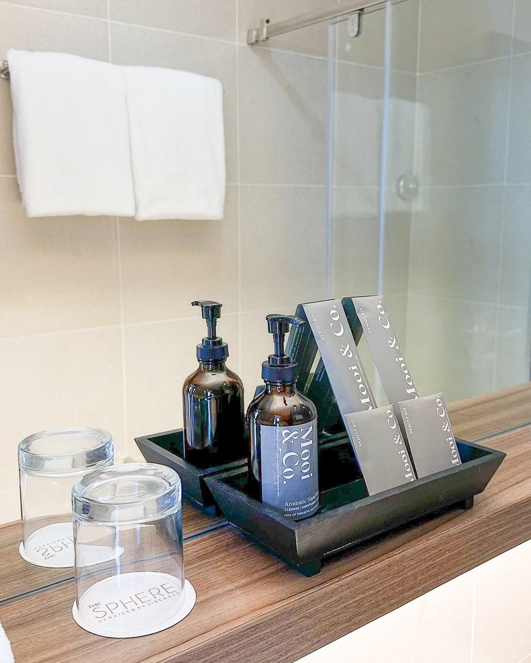 A bathroom counter with a tray of toiletries and glasses.