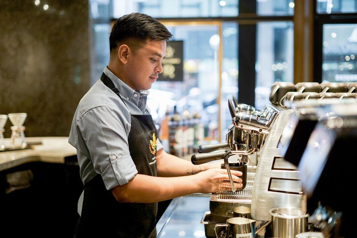 A man making coffee  at a cafe nearby the sphere