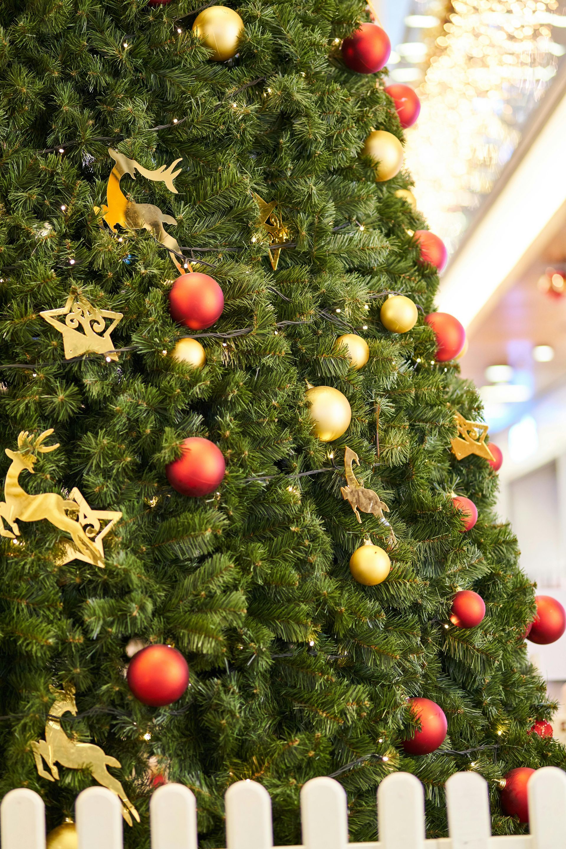 Christmas tree decorated with red and gold ornaments, and gold deer and star decorations.