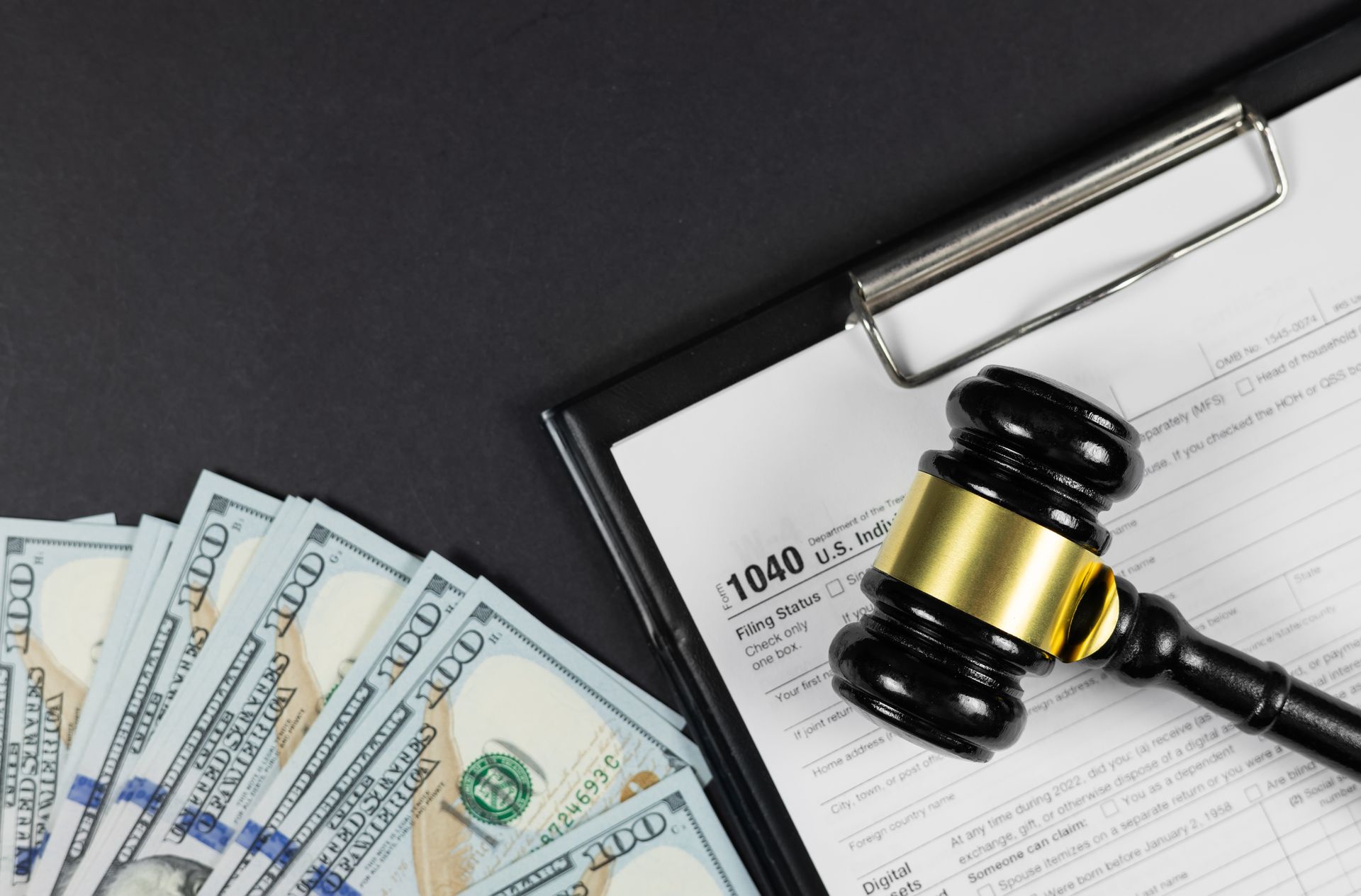 Black gavel on top of tax form with a fan of US dollar bills.