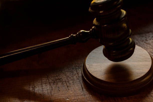 Wooden gavel on a wooden sound block, side view, in dim lighting.